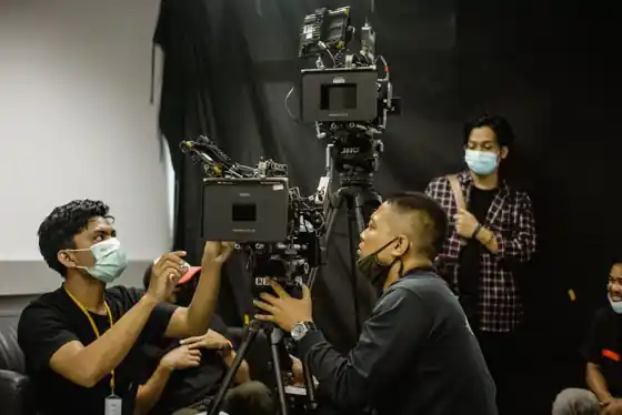 Film production crew running a commercial shoot with camera and lighting on a set