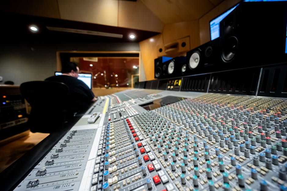 Audio engineer at a mixing console inside a professional recording studio control room