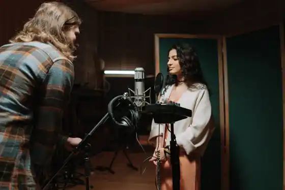 Vocalist recording in a professional music studio with a condenser microphone