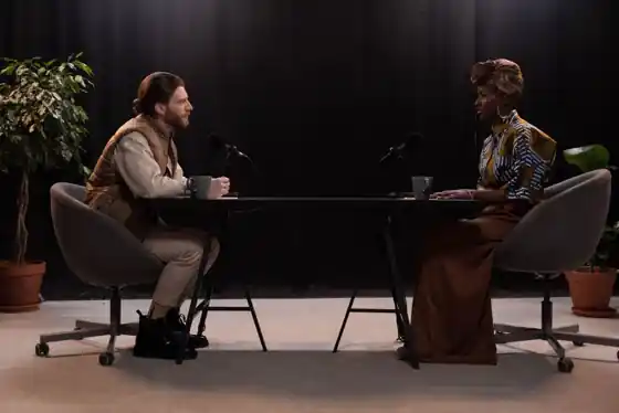 Two people recording a podcast in a professional studio with multiple microphones