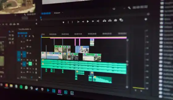 Video editor working on a timeline across two monitors in an editing suite
